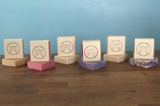 Multiple soap bars with visible branding on a wooden surface against a blue wall.